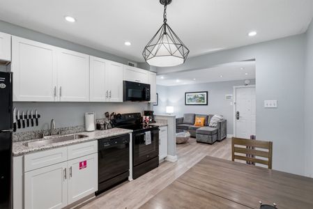 Whip up home-cooked meals in this modern kitchen w/ white cabinetry & black appliances.
