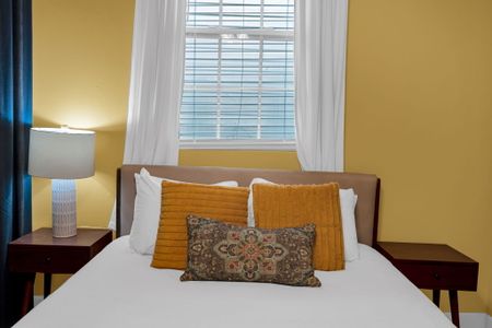 Warm bedroom w/ mustard & white pillows layered for comfort & style.