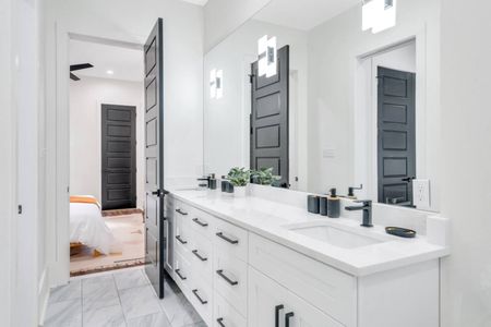 Elegant double-sink bathroom w/ marble walls & warm-toned wood vanity.