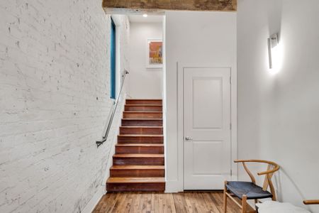 Exposed brick, warm wood tones, and modern touches—this inviting stairway leads to your cozy New Orleans retreat.