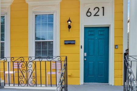 Vibrant yellow exterior w/ a teal door & classic ironwork — full of character.