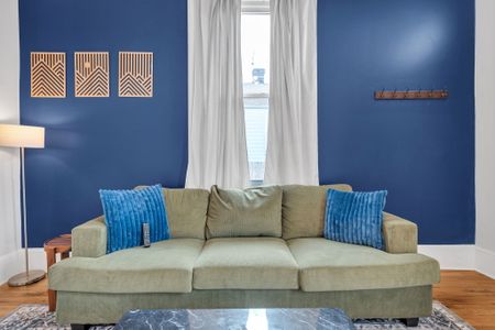Bright living room w/ a bold navy accent wall & cozy seating for relaxing.