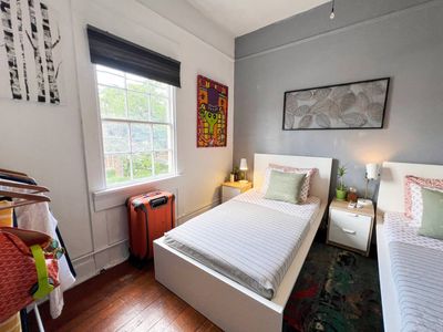 Cozy single bed tucked into a bright, compact room w/ natural light.