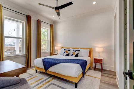 Bright first-floor master bedroom w/ a cozy bed & warm natural light.