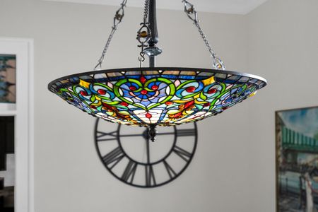 Stained-glass chandelier casting warm, colorful light — a stunning centerpiece.