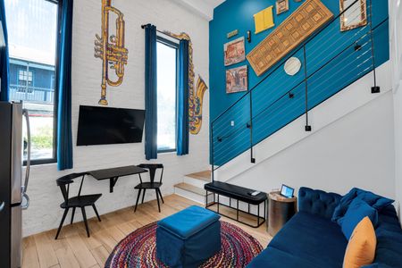 Bold teal walls & a mounted TV set the mood in this jazzy, New Orleans-inspired room.