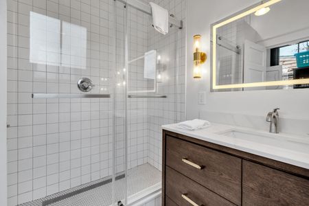 Sleek walk-in shower w/ floor-to-ceiling modern tile.