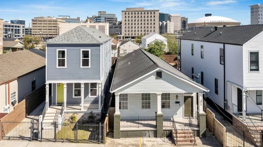 Charming exterior of the home w/ classic New Orleans architecture & green seating out front.