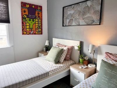 Warm bedroom w/ cozy bedding & lively wall art for a personalized touch.