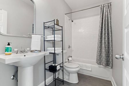 Well-organized bathroom w/ a tub/shower combo & open shelving.