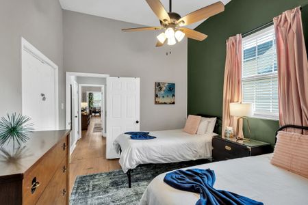 Serene bedroom w/ a bed, ceiling fan & dark green accent wall for a calm retreat.