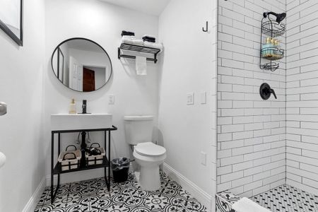 Stylish bathroom w/ a round mirror, tiled walls & a sink — fresh & modern.