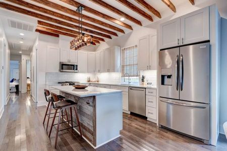 Sleek white kitchen w/ stainless appliances & island seating for casual mornings.