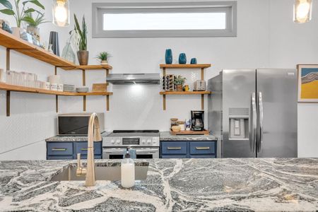 Stylish kitchen w/ open shelving, bold tile backsplash, & stainless appliances ready to use.