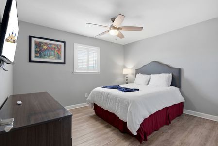 Sun-filled primary suite w/ a plush bed & clean, crisp finishes.