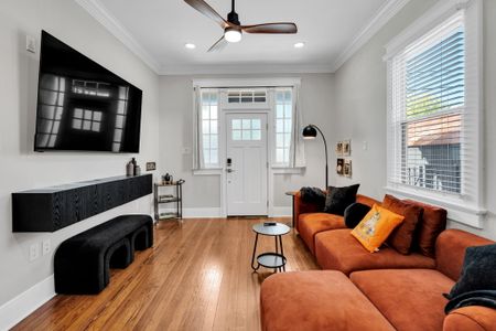 Kick back on the plush orange sectional in this bright living room w/ warm wood floors & a light-filled front entry