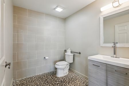 Bathroom w/ toilet, sink & neutral tile.