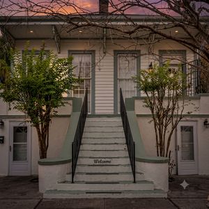 Lush courtyard entrance w/ towering trees & a classic staircase to welcome you home.
