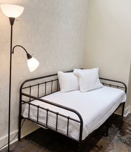 Cozy bed with comfortable bedding and bedside lamp