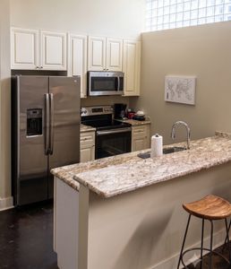 Sleek kitchen w/ granite counters & stainless steel appliances