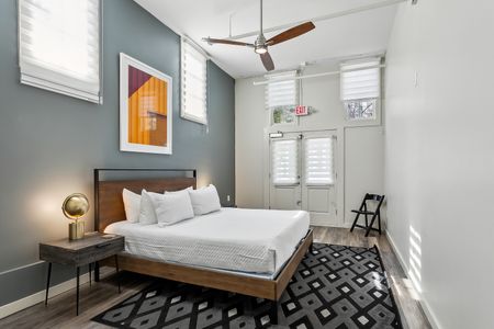 Stylish bedroom w/ statement art, bed & patterned rug.