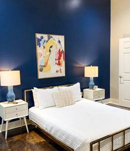 Cozy bedroom w/ bold blue accent wall & vintage-style chair
