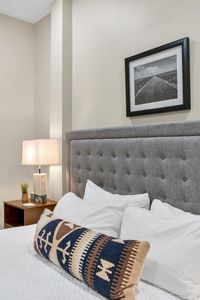 Soft lamp glow beside a plush tufted bed
