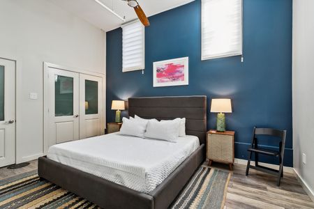 Moody blue bedroom w/ bed & warm bedside lighting.