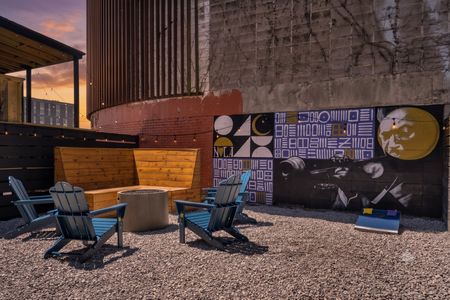 Vibrant outdoor seating area w/ firepit & art-covered walls setting the mood.