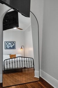 Unwind in this inviting bedroom w/ warm lamp light, bold artwork & a classic iron bed