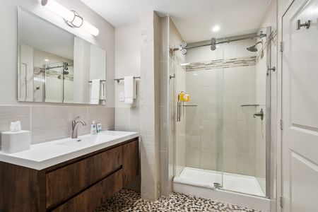 Bathroom w/ glass shower, sink & mirror.