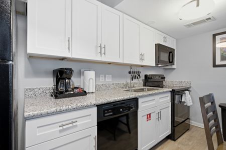 Sleek kitchen w/ granite counters, white cabinetry & full appliances.