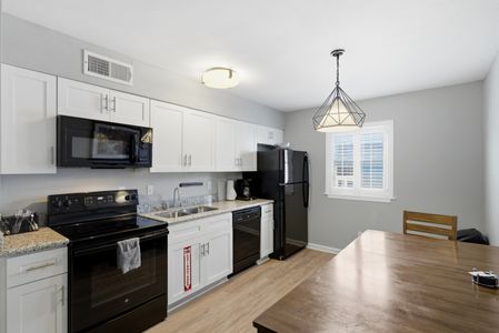 Sleek kitchen w/ black appliances & a dining area ready for home-cooked meals & good company.