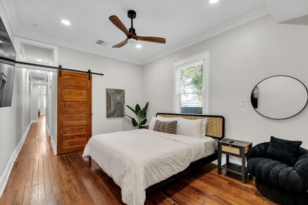 Drift off in this airy bedroom w/ a rustic sliding barn door, ceiling fan & soft natural light