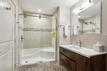 Bathroom w/ glass shower & tub combo, sink & vanity.