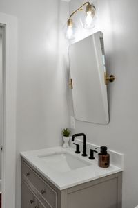 Get ready at the clean, bright vanity w/ a round mirror & modern black fixtures