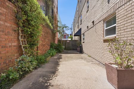 Lush courtyard walkway w/ greenery-lined walls leading to the pool.