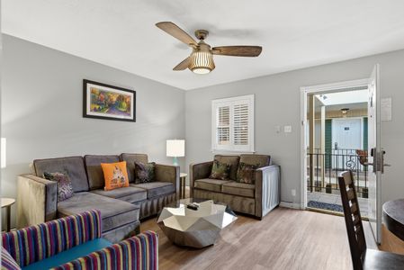 Airy living room w/ ceiling fan & entryway view