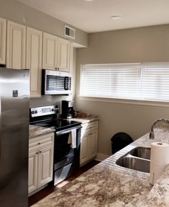 Open kitchen w/ granite island seating & pendant lighting