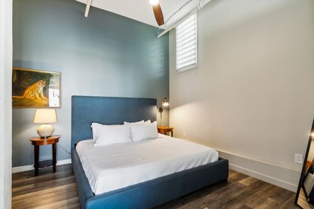 Serene bedroom w/ blue accent wall, bed & soft white linens.
