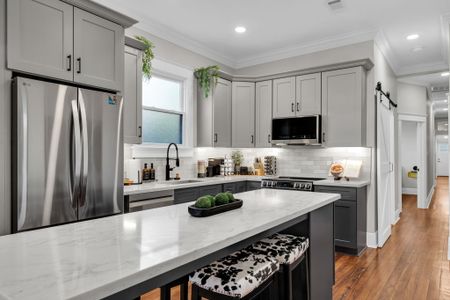 Whip up meals in the sleek kitchen w/ stainless appliances, gray cabinets & a crisp white island