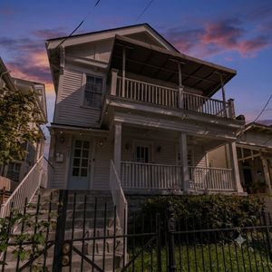 Charming two-story home w/ a wraparound balcony & lush surroundings.