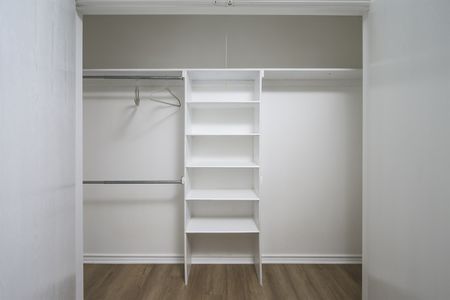 Empty white closet with shelves and hanging rods, showcasing comfort and convenience in a modern