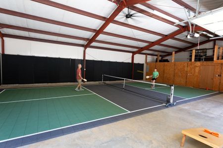 Indoor pickleball court featuring two players engaged in a match, showcasing a green and black