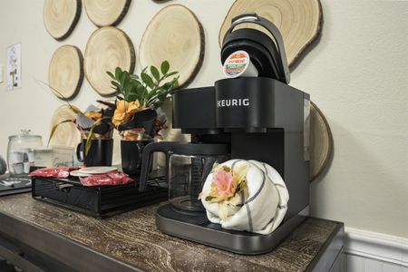 Keurig coffee maker on a wooden table, surrounded by decorative wooden slices, a glass carafe