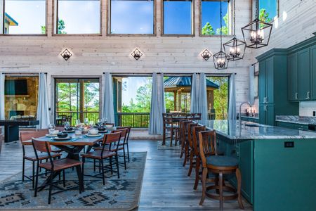 Open-plan dining area and kitchen with green cabinets and large windows
