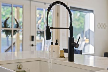 Modern kitchen featuring a black pull-down faucet and a white farmhouse sink, showcasing the luxury