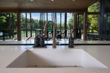 Modern kitchen sink with stylish fixtures overlooking a spacious outdoor deck and lush pine forest