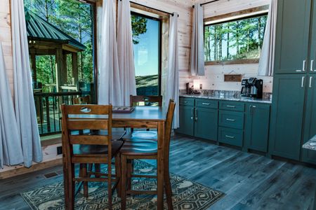 Wooden dining chairs beside green kitchen cabinets and windows
