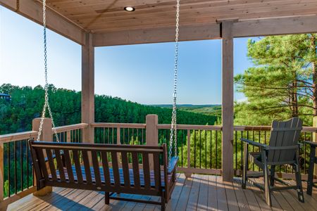 Wooden swing seat on a covered deck overlooking forested hills